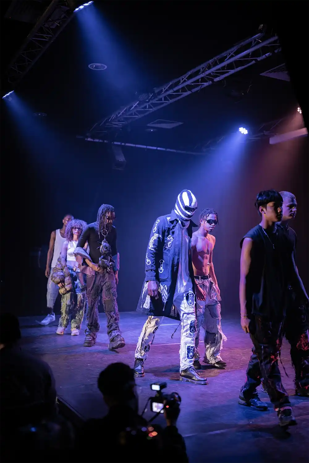 Finale lineup: PrototypesParis looks with graphic trench, Relic Denim, and patchwork jeans—blue stage lighting.