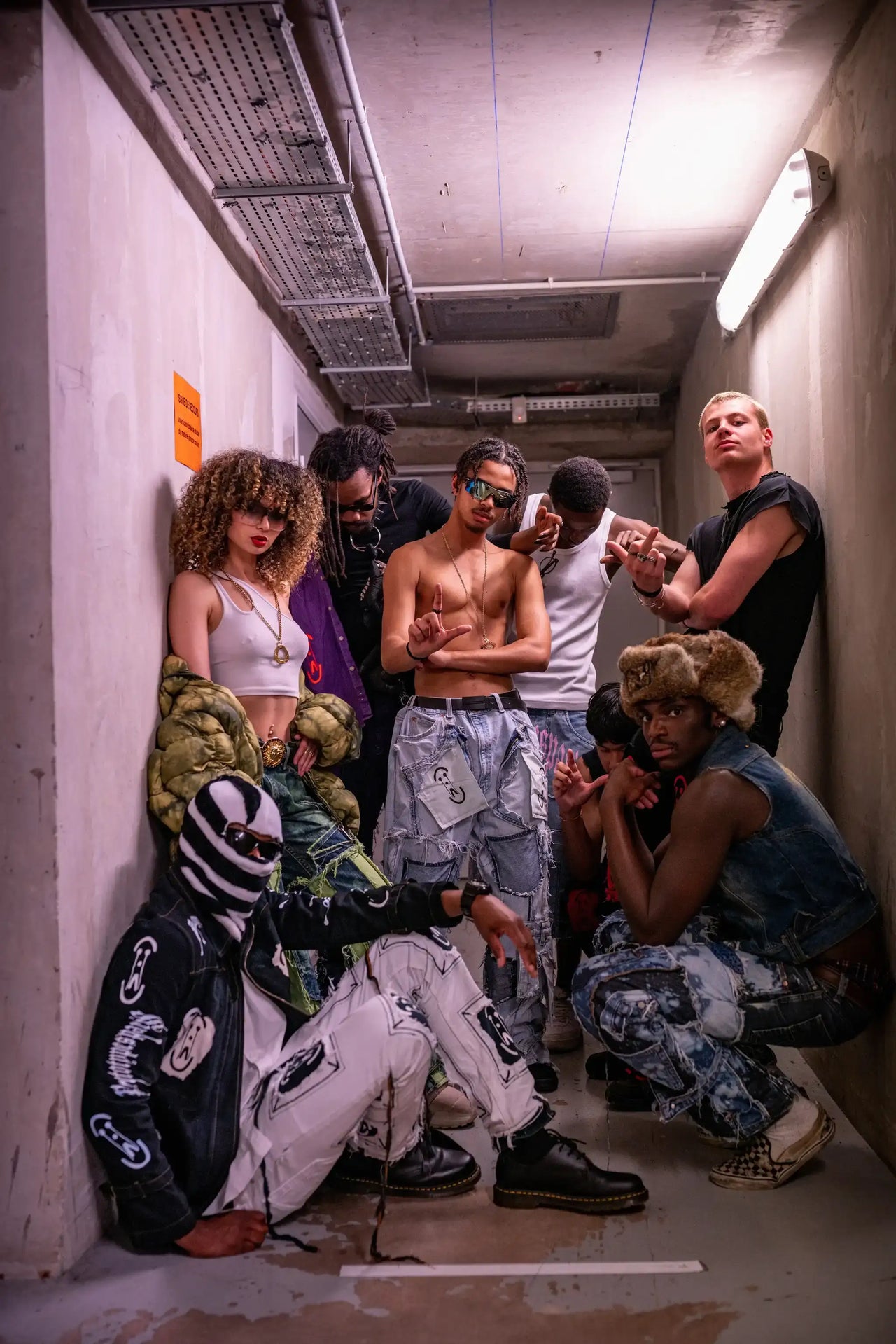 PrototypesParis runway models posing backstage in 1/1 upcycled denim and brutal streetwear, after the show, in a raw concrete corridor.